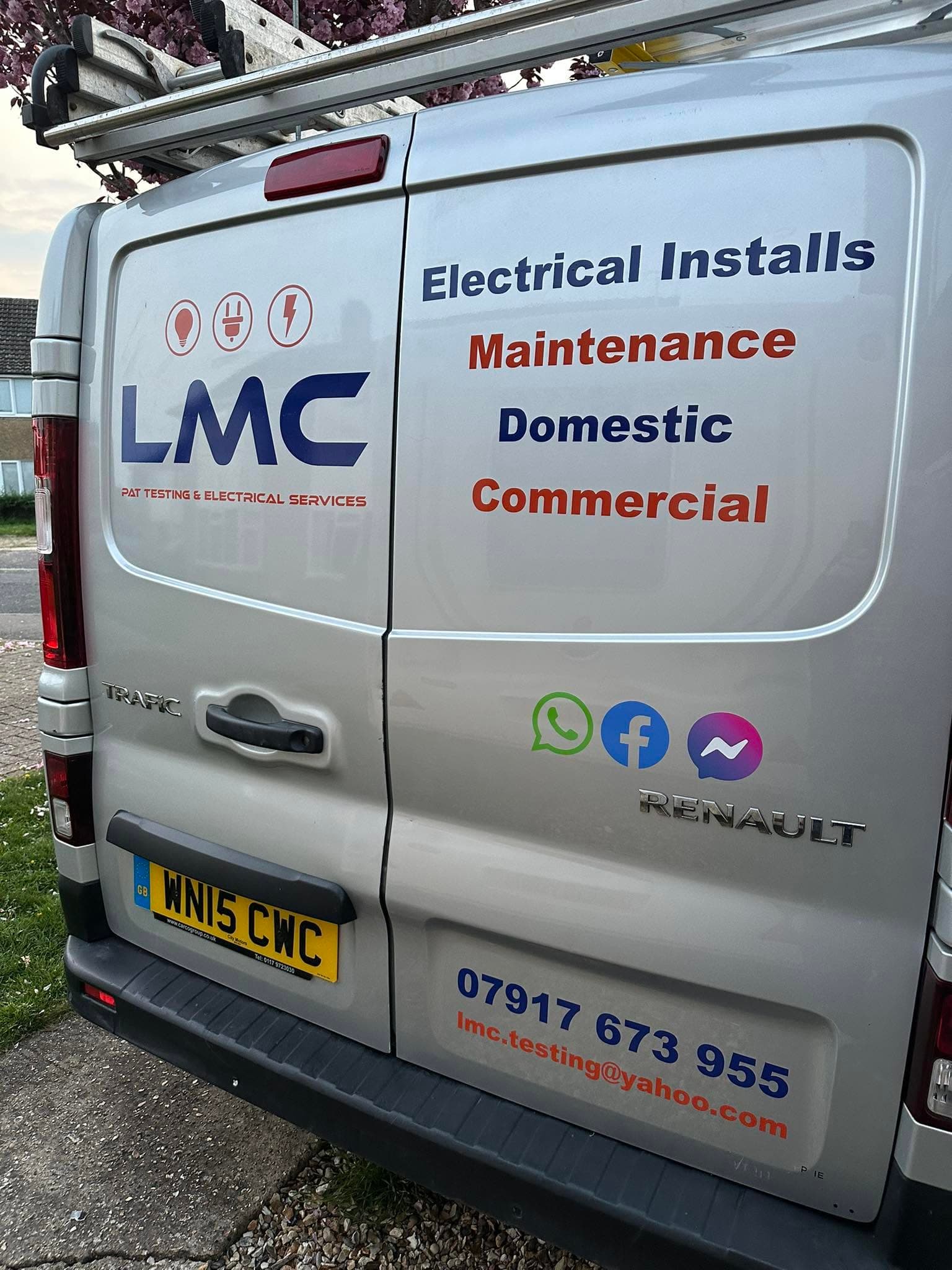 Silver Renault van with LMC electrical services branding, contact details, and ladders on the roof.